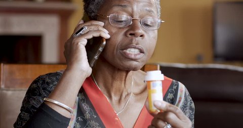Happy smiling black woman over 50 talking and completing her prescription drug order on her cell phone with her pharmacy
