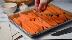 Cooking sweet potato wedges, fries on a baking pan. Hand adding spices.  - Powered by Shutterstock - Get 15% off with code: PIKWIZARD15