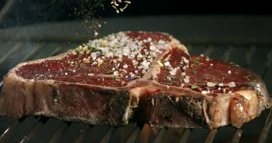 Super slow motion macro of mixed herbs spices and salt grains falling on bio juicy beef steak with rosemary on bbq grill before being cooked on fire by chef in restaurant at 1000 fps. Royalty-Free Stock Footage #3395907127
