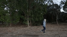 girl with a backpack on her back walking along the trees, view from the side. full hd, 25fps