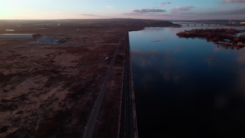 Dark boundless landscape with calm river after sunset. Remote expanse far removed from urban settlements. Industrial district located in unpopulated area