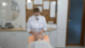Blurred, defocused, blur video. Beauty clinic. Beautician in gloves making face aging injection in a female skin. A woman gets beauty facial cosmetology procedure