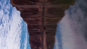 Colorado River and Red Sandstone Cliffs on Sunny Day. Wall Street Rock Climbing Area. Clouds Reflection in Water. Grand County, Utah, USA. Aerial View. Drone Flies at Low Level. Vertical Video
