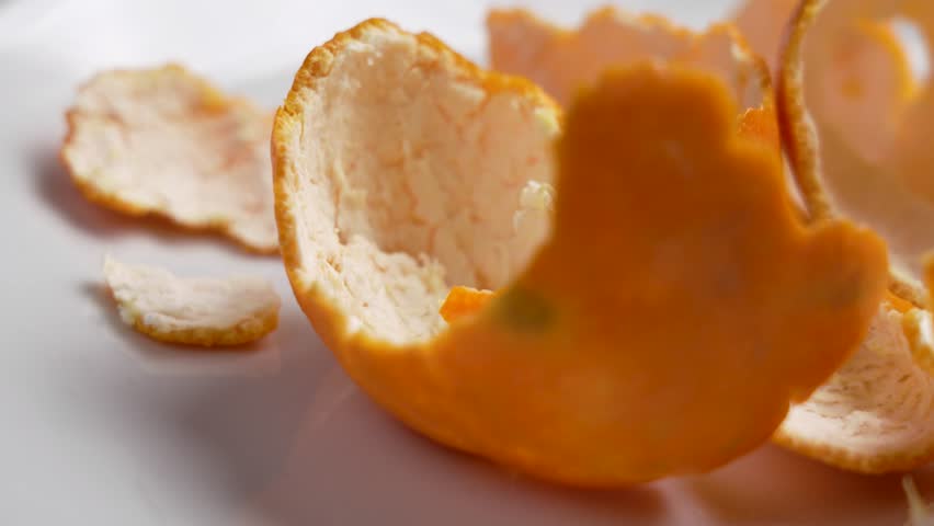 Orange tangerine peelings on white ceramics. Christmas holiday worries concept. Rotation