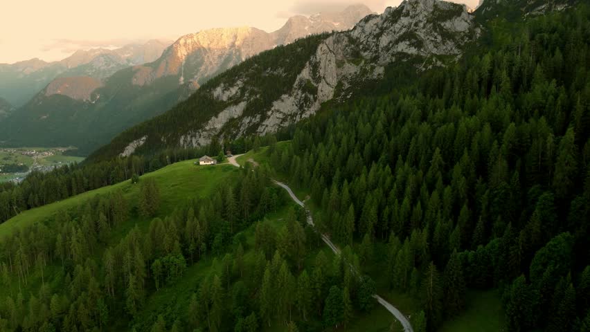 Small hut on a ledge in front of massive cliff during sunset in the Alps in Lofer, Austria.