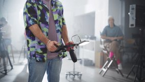 Portrait of Enthusiastic Male Videographer Filming a Project Using Smartphone Rig Equipment in a Bright Studio. Professional Online Content Maker Directing his Actors While Filming Them