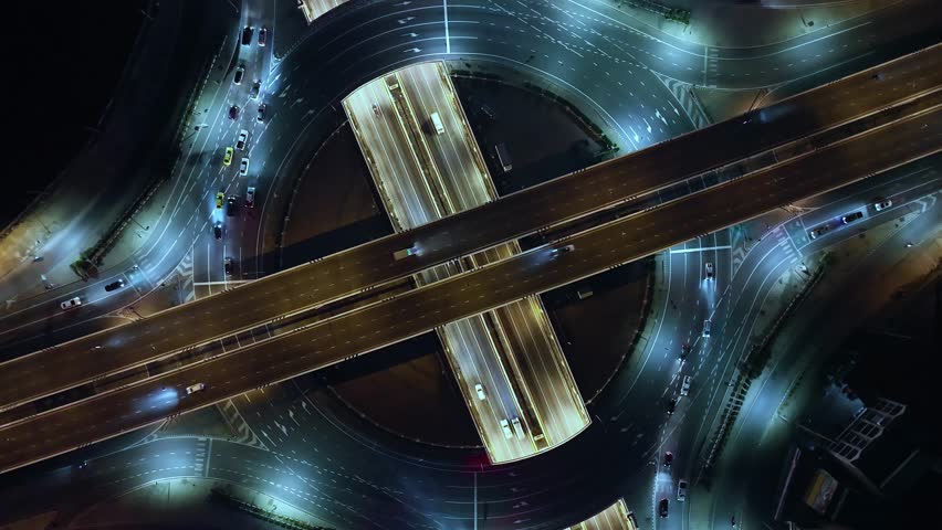 Time-lapse of car traffic transportation on road at junction intersection, 4K. Aerial view of road interchange or highway intersection with busy urban traffic speeding on the road at night. expressway Royalty-Free Stock Footage #3396025561