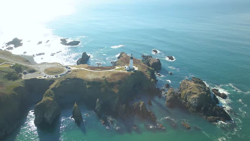 Overhead aerial view of the Yaquina Head Lighthouse surrounded by blue water in Newport, Oregon.
