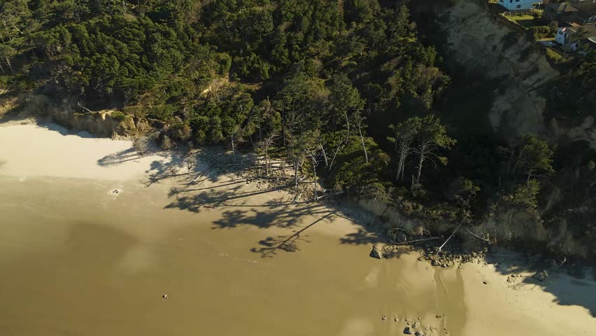 Drone shot pulling back from the beach to reveal the Yaquina Head Lighthouse neighborhood in Newport, Oregon.