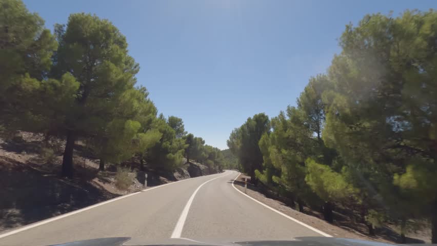 First person view, FPV, from dashcam of car driving mountain road from Calar Alto Observatory to Tabernas Desert in Almeria, Andalusia, Spain, Europe. Road trip in POV, with bright, sunny, clear sky	