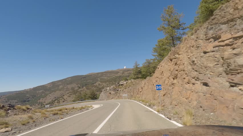 First person view, FPV, from dashcam of car driving mountain road from Calar Alto Observatory to Tabernas Desert in Almeria, Andalusia, Spain, Europe. Road trip in POV, with sharp bend