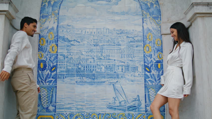 Affectionate newlyweds embracing in ceramic tile place. Hispanic romantic couple flirting hugging at azulejo wall. Happy man woman expressing feelings together. Young carefree lovers enjoying date