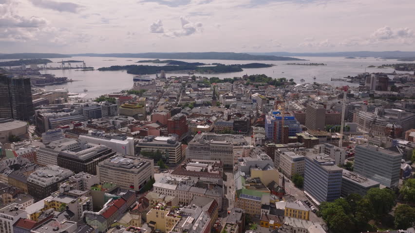 Aerial view of large buildings in urban borough, heading towards coast. Panoramic view of bay with islets and islands. Oslo, Norway Royalty-Free Stock Footage #3396233277