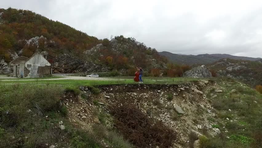 Man plays the cello on the mountains, outdoors. Footage. Musician with a happy look on his face having a break while performing a cello in a field landscape