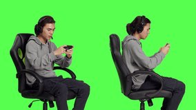 Asian person playing online games on smartphone, sitting in chair over greenscreen. Young guy using phone to play mobile games, online rpg competition with different gamers worldwide.