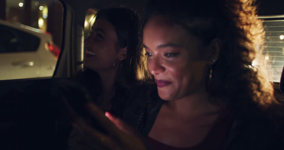 Night, women and taxi travel in a city by woman checking online app, text or message in the backseat. Nightlife, friends and girls laughing while riding in a car, smile and excited while using phone Royalty-Free Stock Footage #3396357825