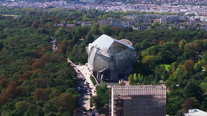 Aerial view of futuristic structure, modern art design of Fondation Louis Vuitton building surrounded by trees in Bois de Boulogne. Paris, France Royalty-Free Stock Footage #3396408617
