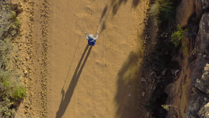 Travel, drone and person trekking in nature with freedom, adventure or walking journey outdoor. Aerial view, landscape and adult hiking on dirt road for vacation, explore or holiday mountain location