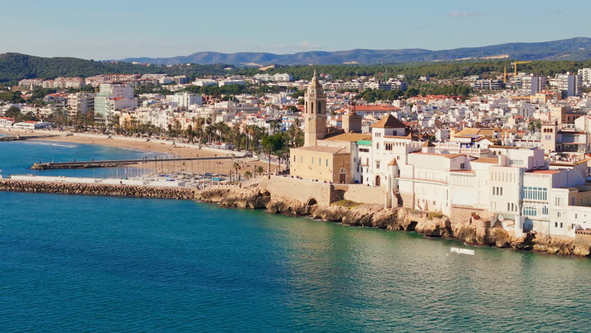 Drone captures charming old church surrounded by sailors' town in sunny weather with a beautiful blue sea coast backdrop