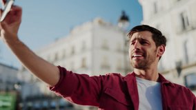 Smiling male blogger holding smartphone in front and talk to camera while make vlogging content. Cheerful tourist man enjoy video calling with roaming 6G internet connection on mobile phone device - Powered by Shutterstock - Get 15% off with code: PIKWIZARD15