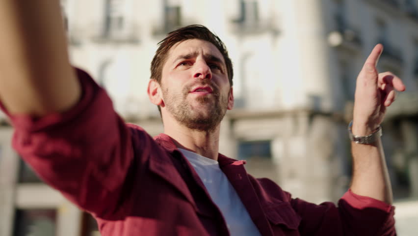 Handsome smiling male creating engaging content to document travel experiences in Madrid square Sol. Smiling man experiencing culture of new city as modern tourist. Enjoying video call technology Royalty-Free Stock Footage #3396529257