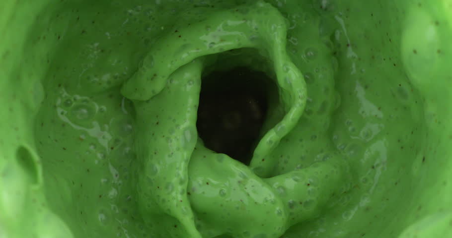 Super slow motion top view of dietetic milkshake smoothie cocktail of bio milk rich with calcium and organic fresh kiwi fruit is being mixed in blender at 1000 fps.