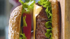 Cooking burger. Close-up, vertical footage. Big appetizing burger with fresh tomatoes, onions, juicy grilled beef patty and cheese. Fast food - Powered by Shutterstock - Get 15% off with code: PIKWIZARD15