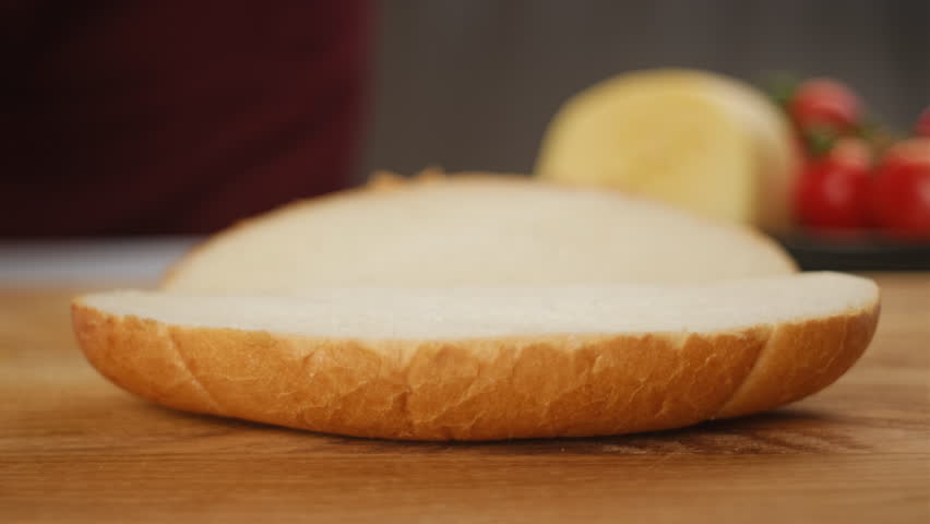 Close up of unrecognizable young woman spreading soft butter on slice of bread. Spreading cream cheese on bread. Housewife making sandwich for breakfast. Food concept Royalty-Free Stock Footage #3396697999