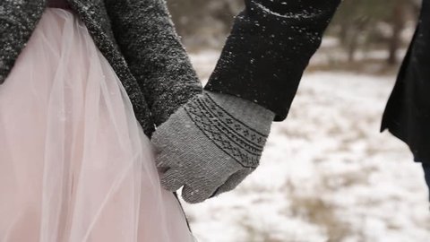 Outdoor winter forest shot of young wedding couple walking and having fun holding hands in snow weather pine forest during snowfall. Snowy engagement ceremony. Bride follows groom. Video compilation
