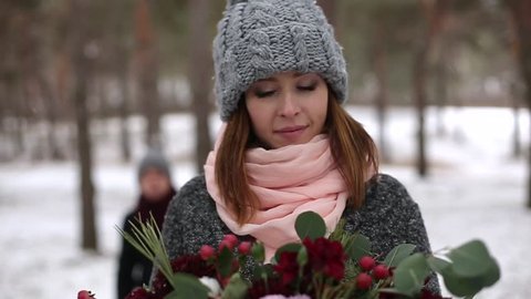 Groom comes to bride, hugs and kiss her from back in snow winter pine forest during snowfall. Romantic wedding engagement ceremony. Christmas and Valentine's Day concept. Video sequence compilation
