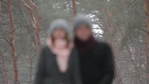 Outdoor winter forest shot of young wedding couple walking and having fun holding hands in snow weather pine forest during snowfall. Snowy engagement ceremony. Video compilation sequence