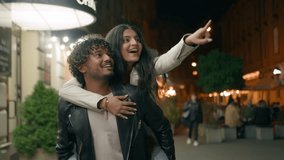 Indian Arabian couple love guy holding girl on back piggyback woman man boyfriend girlfriend walking night evening city looking at beautiful urban architecture pointing excited tourist travel dating - Powered by Shutterstock - Get 15% off with code: PIKWIZARD15