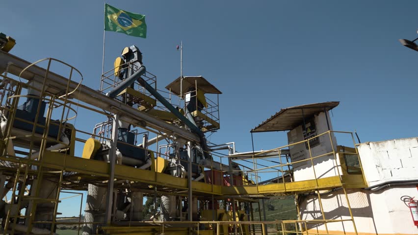Brazilian flag waving in the wind on top of an agricultural machine in a coffee production field