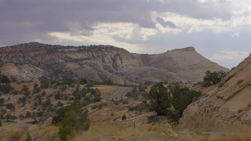 Establishing shot of brown mountains with green forest in The Hogback Scenic Root 12, Utah, North America. Day time on October 2023. ProRes 422 HQ.