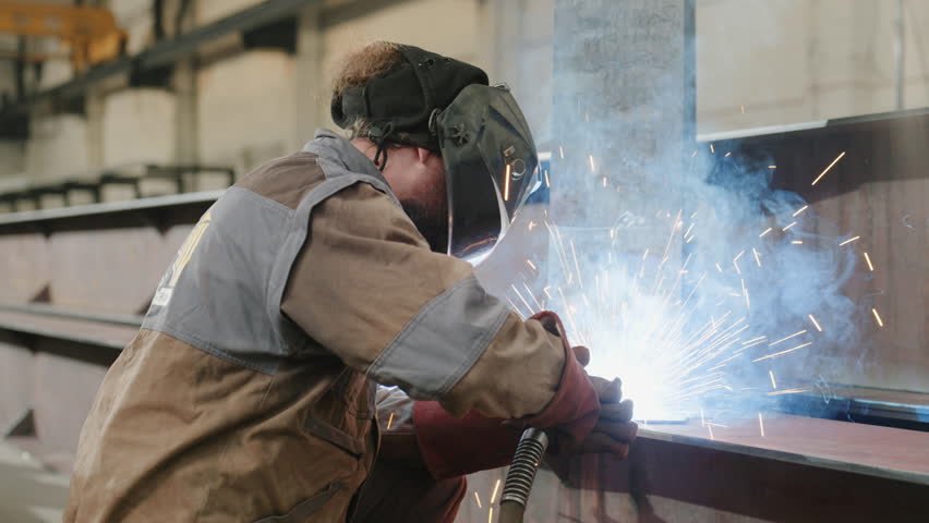 Professional welder man in the metalwork factory welding metal he wearing safety equipment and helmet the sparkles fly everywhere Royalty-Free Stock Footage #3396871079