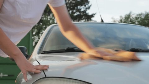 a girl in a white T-shirt wipes the car after washing it at the car wash: film stockowy