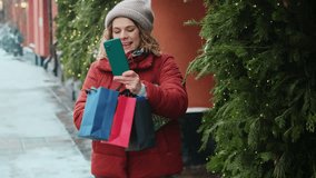 Christmas shopping concept. Woman shows off Christmas purchases during video call outdoors.