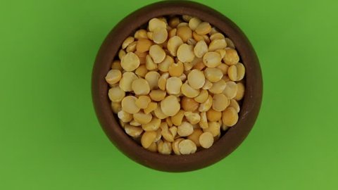 Zoom out, rotation of dry pea grains in a clay pot, isolated