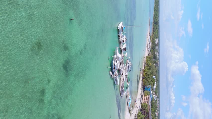 Vertical drone flight over luxury yachts parking at pier of Boca Chica Beach with clear Caribbean sea water