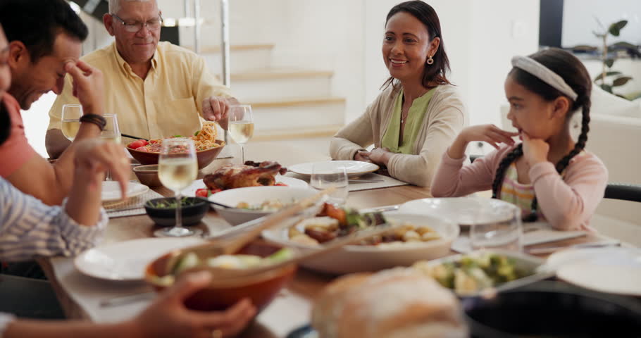 Big family, dinner and happy at dining table with food for bonding, event or conversation in living room of home. Love, grandparents and parents with children for lunch, supper or brunch with cheers