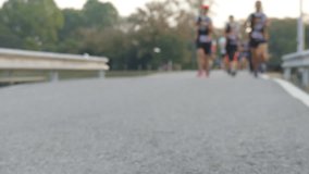4K Blurred video Group of people running in a marathon. Street level close up of  runners feet.