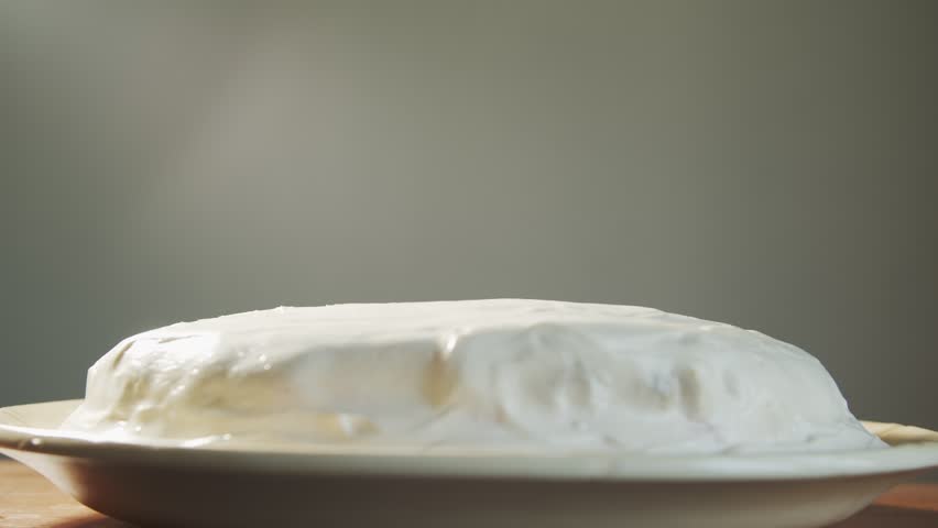 A hand places two fused red cherries on a white cake