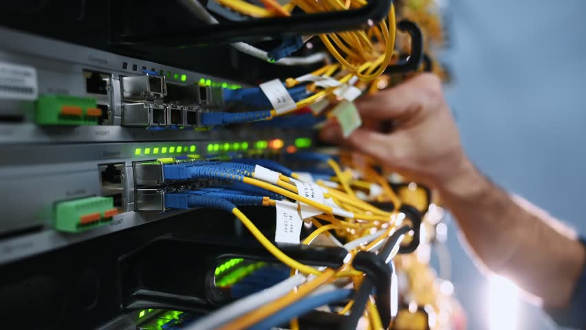 Close up view of hand that fixing internet. Young man is working with equipment and wires in server room Royalty-Free Stock Footage #3397194655