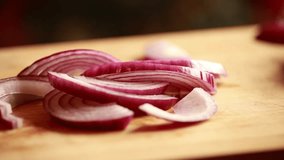Woman's Hand Cutting Red Onion on Wooden Board Close-Up 