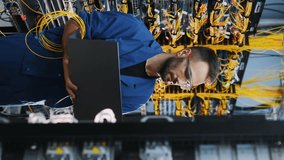 Silver colored laptop in hands. Young man is working with internet equipment and wires in server room - Powered by Shutterstock - Get 15% off with code: PIKWIZARD15