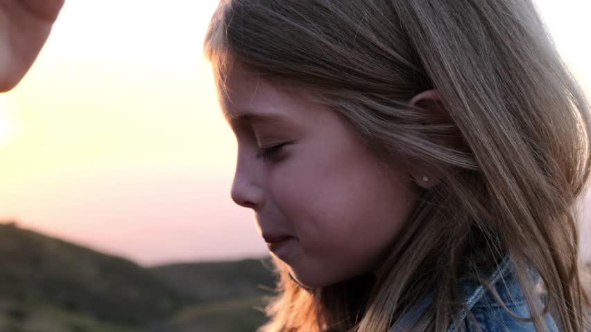 The father's hand strokes his daughter's head against the backdrop of sunset. Royalty-Free Stock Footage #3397354019