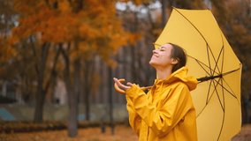 girl take off yellow raincoat hoodie to enjoy falling rain, standing with umbrella in city park looking up to sky enjoying rain drops to her face smiling, feel fresh, season climate change - Powered by Shutterstock - Get 15% off with code: PIKWIZARD15