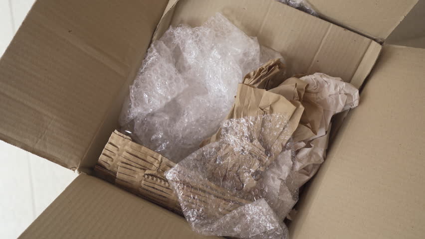 Put bubble wrap and kraft paper into a cardboard box Royalty-Free Stock Footage #3397442925
