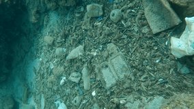 Top view, a lot of plastic debris at the bottom of sea in a crevice between rocks, Vertical video, Slow motion, Rhodes island, Greece