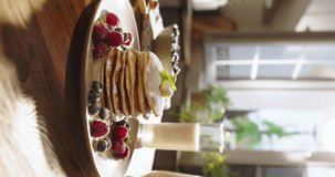 American traditional breakfast pancakes with berries and syrup. Kitchen-themed video, joy of healthy eating recipes for family recipes for every day and weekends. Glass of milk on background. Vertical